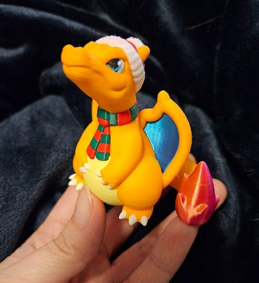 a toy dragon with a hat and scarf sitting in front of snowflakes