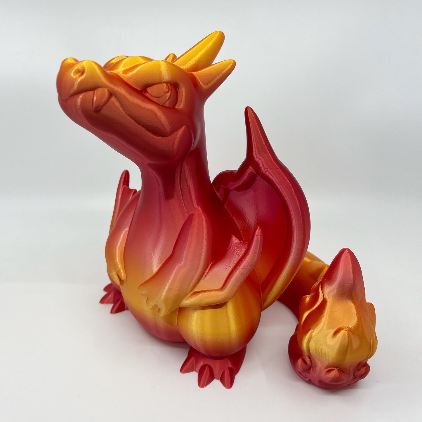 a red and yellow dragon figurine sitting on a white surface